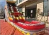 Tall red inflatable waterslide with a splash pool